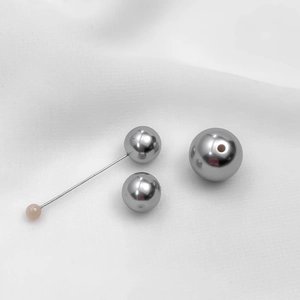 Gray acrylic and glass pearl pendant beads for DIY necklaces on white textured fabric