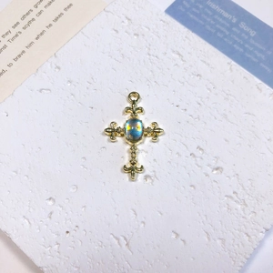 Detailed view of vintage gold cross pendant with opal stone on a stone surface