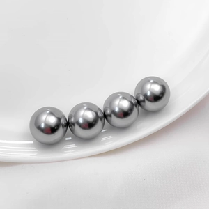 Macro shot of silver-gray high-luster acrylic pearls arranged on white ceramic edge
