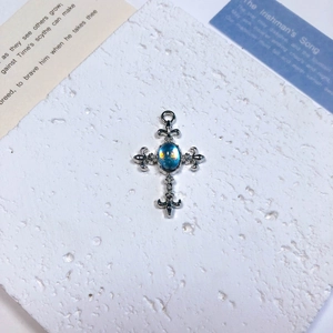 Detailed macro view of a silver alloy cross pendant featuring a radiant blue opal center