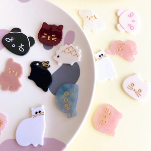 Assorted cute acrylic animal DIY hair accessories featuring cats and rabbits in a ceramic plate