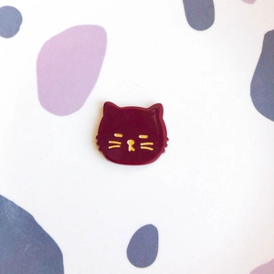 Vue détaillée d'un accessoire en acrylique chat rouge foncé avec détails dorés