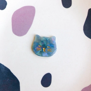 Détail d'un charme chat en acrylique marbré avec moustaches dorées pour bijoux DIY