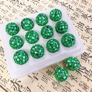 Detailed macro view of faceted green crystal beads arranged on a white display tray