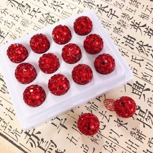 Macro detail of red faceted clay beads with sparkling finish on a white tray