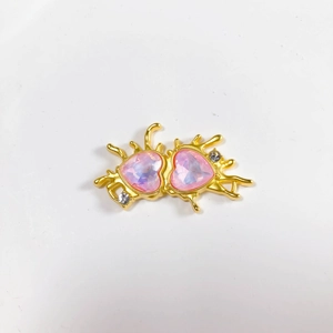 Detail of gold alloy heart pendant featuring pink crystals and fluid metal design