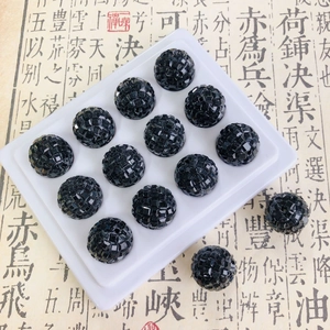 Detailed view of faceted black disco ball beads on a white tray for DIY accessory making