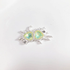 Detail of silver fluid metal heart charm with light green crystals and small rhinestones