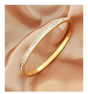 Close-up of gold titanium steel bangle with inlaid square crystals on champagne silk
