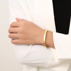Detail van een gouden armband met hartgravure en kristallen gedragen door een model