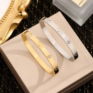 Gouden en zilveren roestvrijstalen armbanden met hartgravure en kristallen op een doosje