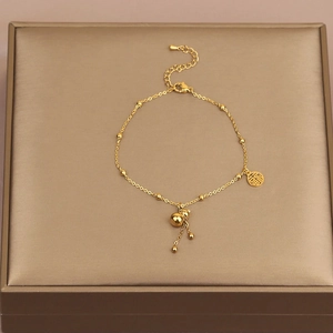 Détail de la chevillère en acier titane avec pendentif gourde dorée et breloque Fu