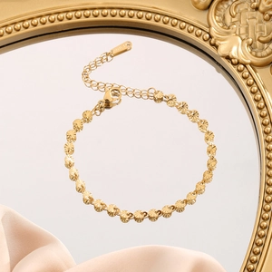 Gold titanium steel bracelet set with textured circular discs on a luxury mirror surface