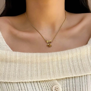 Elegante gouden strikketting met belletjes bij model met witte gebreide trui