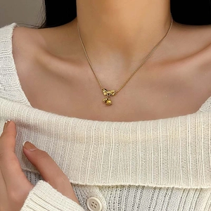 Gouden lelietje-van-dalen strik ketting van titanium staal om een vrouwenhals