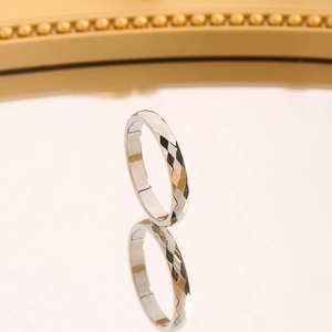 Detail of faceted silver ring with light-reflecting geometric surface design