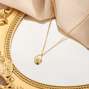 Elegant gold titanium steel necklace with avocado shell pendant on a vintage mirror