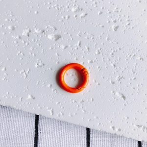 Close-up of a 20mm bright orange metal spring O-ring for DIY bags and keychains