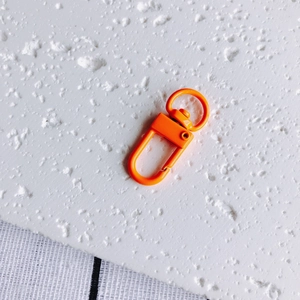 Vue macro d'un fermoir mousqueton orange vif avec finition laquée et anneau rotatif en D