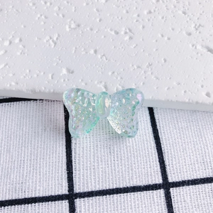 Macro shot of iridescent resin butterfly charm with glitter detail on grid fabric