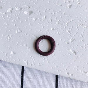 Close-up of matte dark purple round spring ring clasp for DIY jewelry and bag hardware