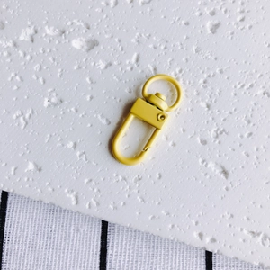 Détail d'un fermoir mousqueton en métal jaune vif avec anneau rotatif à 360 pour artisanat DIY