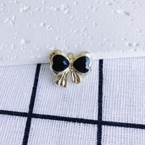 Macro view of golden bow pendant with two black heart-shaped gemstones for DIY jewelry