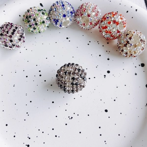 Makroansicht bunter Disco-Perlen mit Strasssteinen auf weißem Teller für DIY-Schmuck