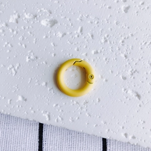 Detail of a matte yellow round spring o-ring hook for DIY keychains and bag accessories