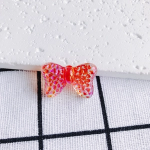 Macro detail of translucent orange resin butterfly charm with iridescent glitter inlay