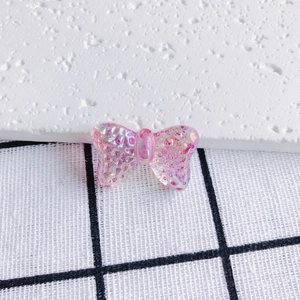 Detail of pink transparent bow pendant with iridescent glitter for DIY jewelry making