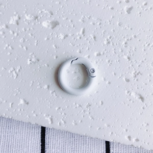 Detail of white matte spring ring buckle on a textured background for DIY crafts