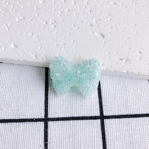 Dettaglio macro di ciondolo a fiocco in acrilico glitter menta per gioielli DIY