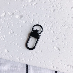 Détail d'un fermoir mousqueton en métal noir avec anneau pivotant pour porte-clés DIY