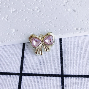 Macro shot of bow-shaped pendant with pink heart crystals and gold metal setting