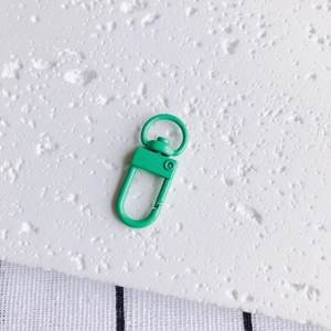Détail macro d'un fermoir mousqueton en métal vert mat avec anneau pivotant pour artisanat