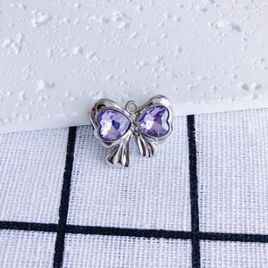 Macro detail of purple heart zircon bow pendant with silver-tone textured metal