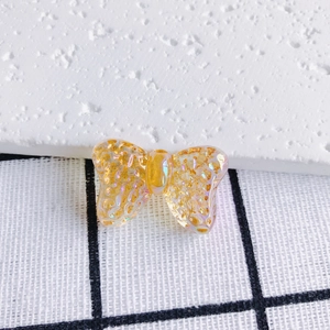 Macro shot of amber gold iridescent bow charm with honeycomb texture for DIY jewelry