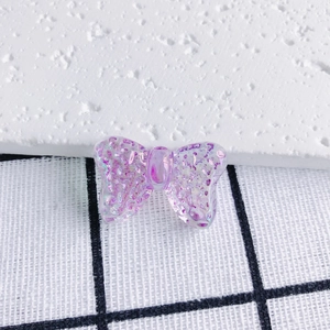 Detail of transparent iridescent purple bow pendant with glitter for DIY jewelry making