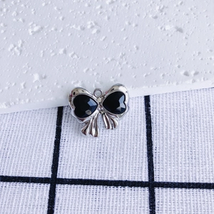 Detail of silver bow pendant with black inlay and metallic ring loop for DIY jewelry