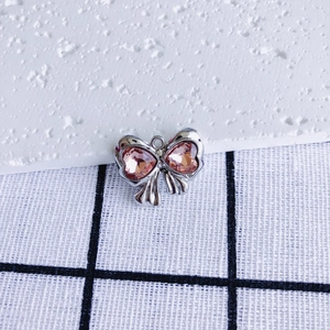 Detailed view of silver bow pendant with pink heart crystals and top attachment hole