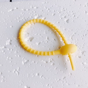 Makro-Detail des verstellbaren gelben Silikon-Kabelbinders mit Zahnstruktur und Verschluss