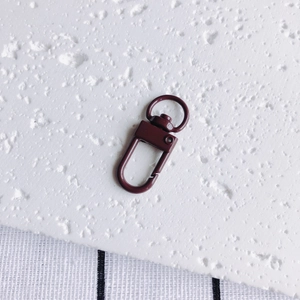 Détail du fermoir mousqueton rouge foncé avec finition laquée sur surface texturée