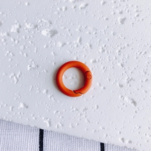 Detail shot of a vibrant orange round spring clasp with a matte painted finish for DIY