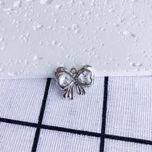 Macro detail of a silver bow pendant with heart-shaped zircon stones and a circular ring