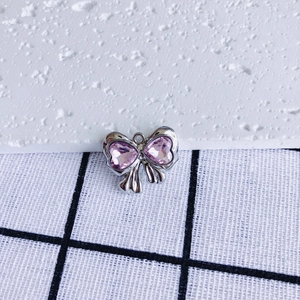 Detail shot of silver bow pendant featuring two pink heart-shaped zircon stones