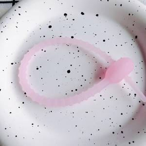 Detailaufnahme eines flexiblen rosa Silikon-Kabelbinders auf einem gepunkteten Teller