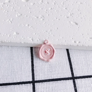 Macro shot of a pink button-shaped alloy pendant with a wax seal inspired design and top ring