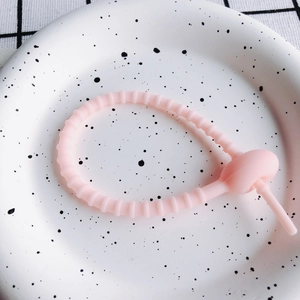 Nahaufnahme eines rosa verstellbaren Silikon-Kabelbinders mit matter Textur auf einem Teller