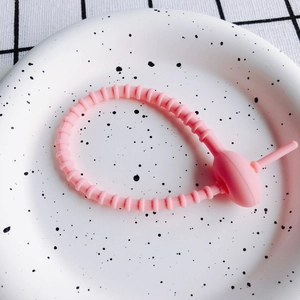 Detailaufnahme eines flexiblen rosa Silikon-Multifunktions-Kabelbinders mit Schnallen